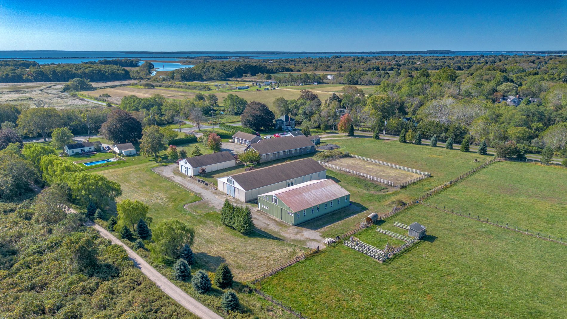 Spring drone view over the full estate — buildings, fields and tree lines
